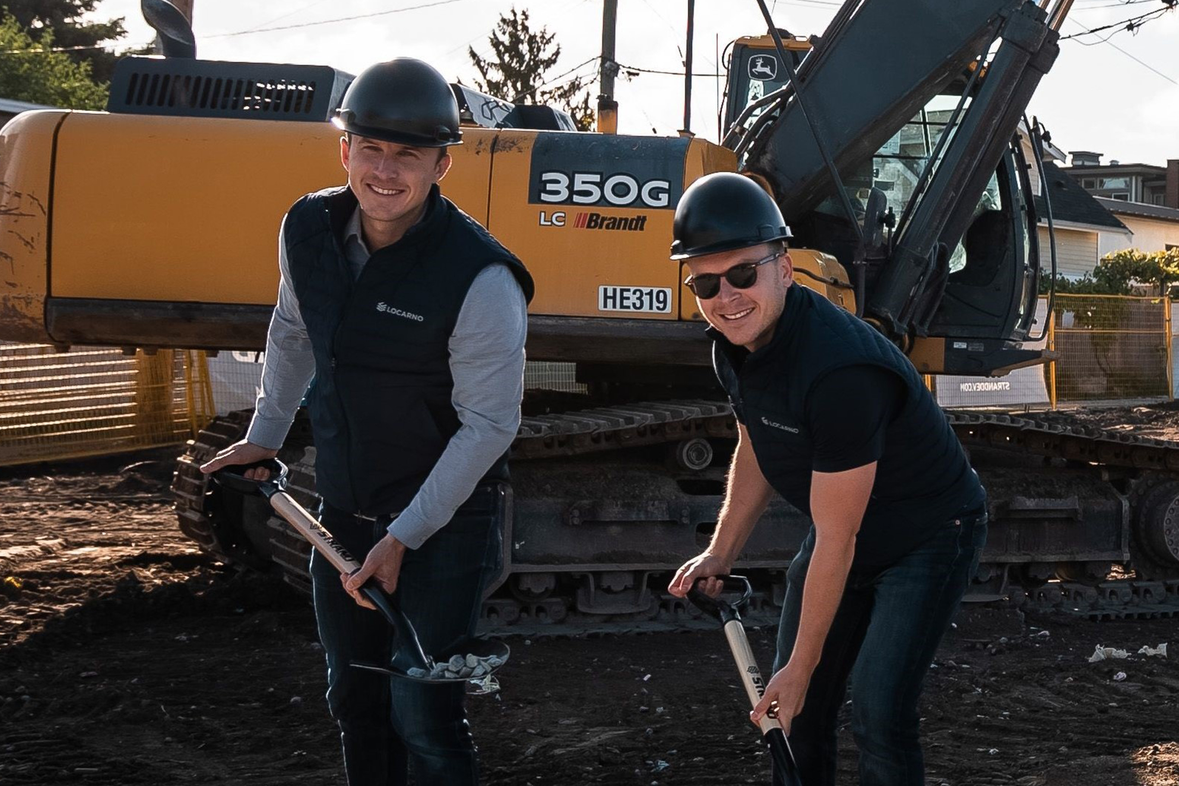 Two smiling construction workers digging at construction site